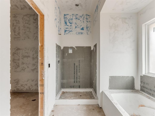 full bath featuring a garden tub and unfinished concrete floors