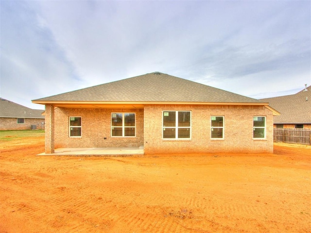 back of house with a patio, brick siding, a shingled roof, and fence