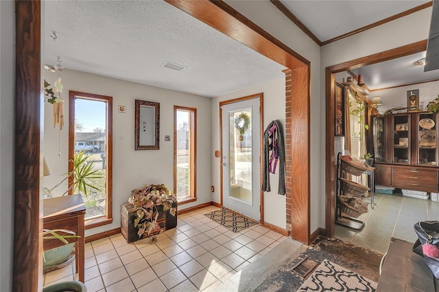 tiled foyer with ornamental molding, a textured ceiling, and baseboards