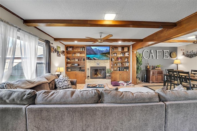 living room with built in shelves, a fireplace, ceiling fan, a textured ceiling, and beamed ceiling