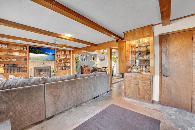 unfurnished living room with concrete floors, beamed ceiling, a textured ceiling, and a glass covered fireplace