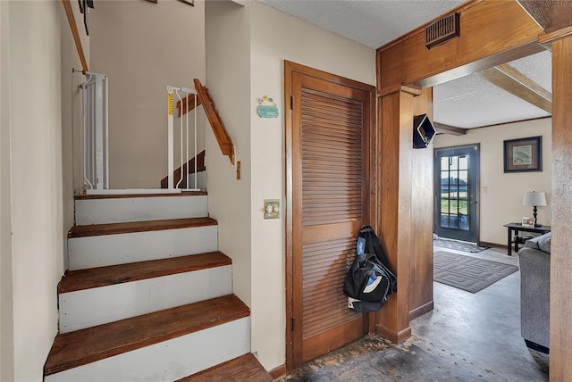 stairs featuring visible vents, concrete flooring, and a textured ceiling