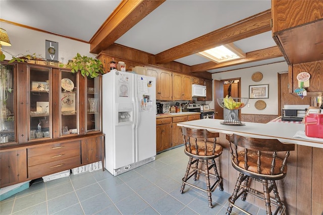 kitchen featuring white appliances, brown cabinetry, beamed ceiling, a peninsula, and light countertops