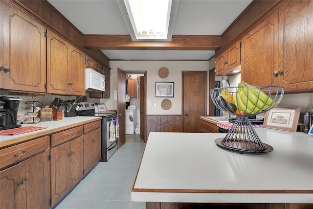 kitchen with stainless steel electric stove, light countertops, white microwave, wainscoting, and beamed ceiling