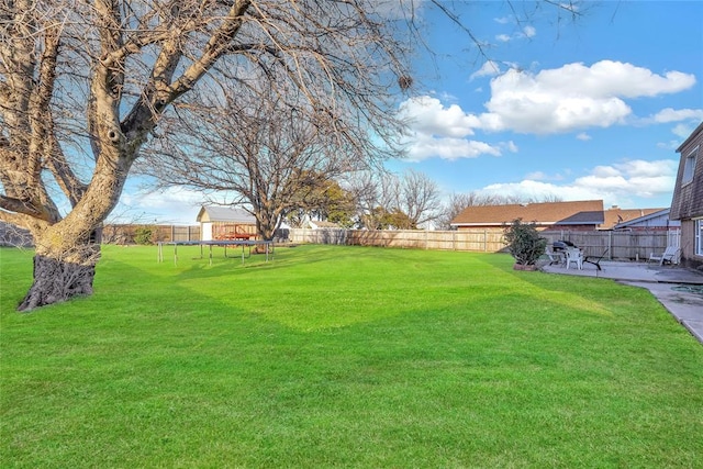 view of yard with a fenced backyard, a trampoline, and a patio