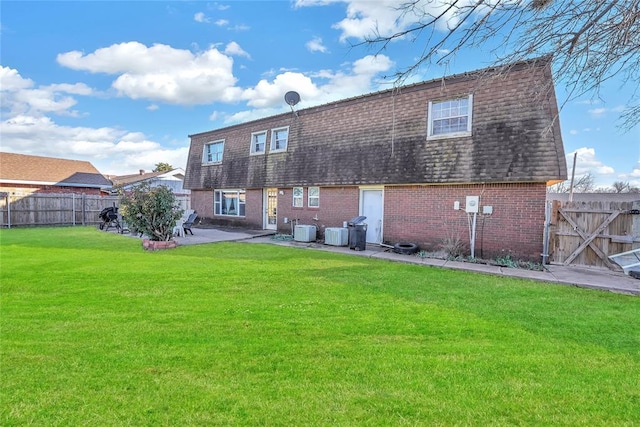 rear view of property featuring brick siding, roof with shingles, a lawn, a patio area, and fence