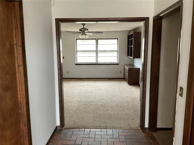 corridor featuring dark colored carpet and baseboards