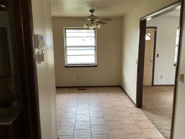 unfurnished room featuring light tile patterned floors, visible vents, a ceiling fan, a textured ceiling, and baseboards