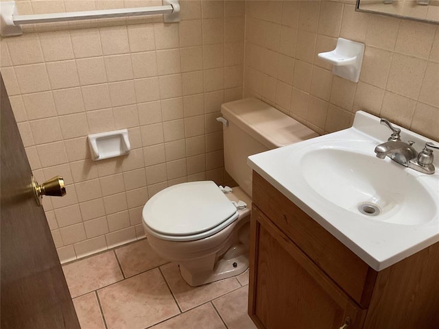 half bathroom with tile patterned flooring, tile walls, vanity, and toilet