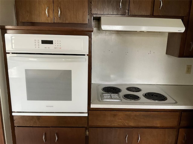 kitchen featuring light countertops, dark brown cabinets, under cabinet range hood, and white electric cooktop