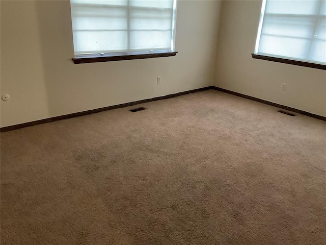 carpeted empty room featuring visible vents and baseboards