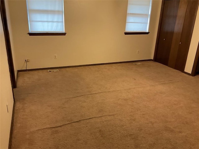 unfurnished bedroom featuring baseboards, a closet, visible vents, and carpet flooring