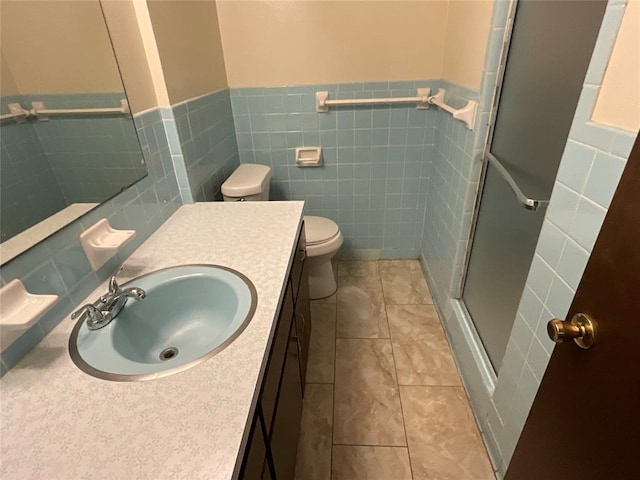 bathroom featuring toilet, vanity, wainscoting, a shower stall, and tile patterned floors