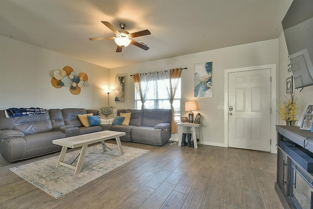 living room featuring ceiling fan, wood finished floors, and baseboards