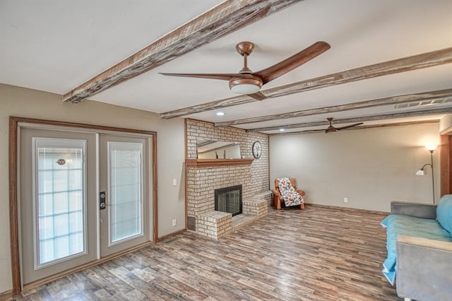 unfurnished living room featuring ceiling fan, wood finished floors, beamed ceiling, french doors, and a fireplace