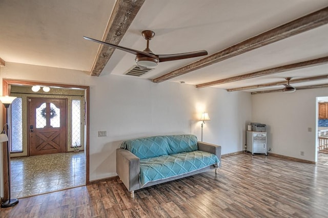 interior space featuring a ceiling fan, beam ceiling, baseboards, and wood finished floors