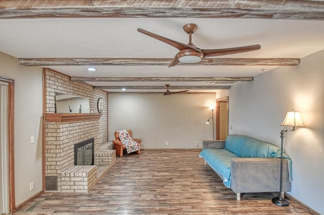 living area with baseboards, ceiling fan, beamed ceiling, wood finished floors, and a fireplace