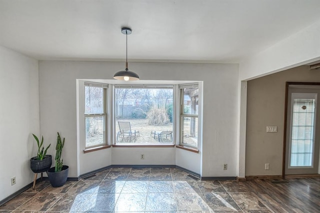 unfurnished dining area featuring stone finish flooring, visible vents, and baseboards