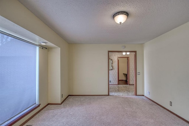 spare room featuring a textured ceiling, carpet floors, and baseboards