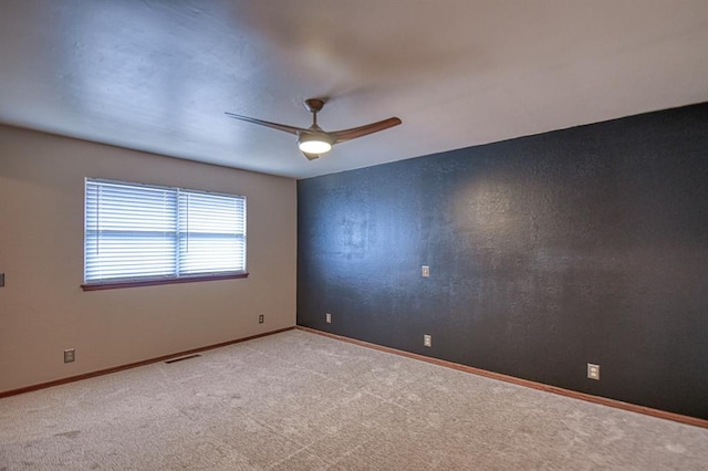 carpeted spare room featuring visible vents, ceiling fan, and baseboards