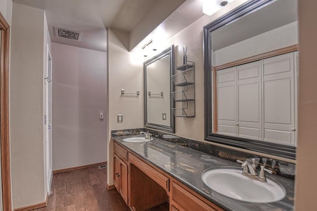 bathroom featuring double vanity, visible vents, a sink, and wood finished floors