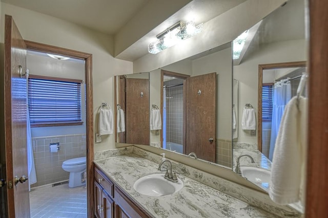 full bathroom with tile walls, toilet, wainscoting, vanity, and tile patterned flooring