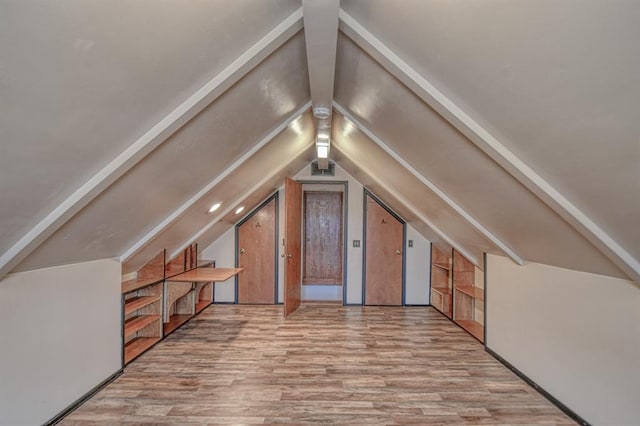 bonus room featuring vaulted ceiling with beams and wood finished floors