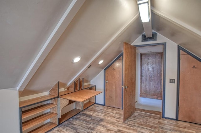 additional living space featuring lofted ceiling, stairs, visible vents, and wood finished floors