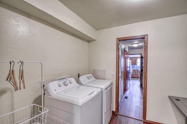 clothes washing area with a textured wall, laundry area, separate washer and dryer, and dark wood-style flooring