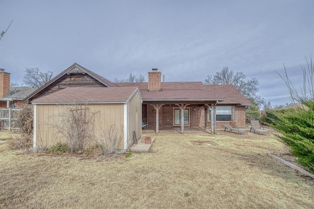 view of front of property with a chimney, a storage unit, a patio area, an outdoor structure, and a front lawn