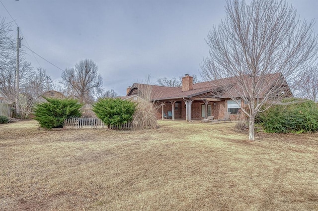 view of front of property featuring a chimney, fence, a front lawn, and brick siding