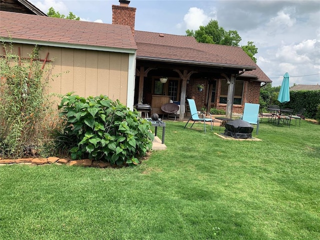 rear view of property featuring a chimney, a lawn, and brick siding