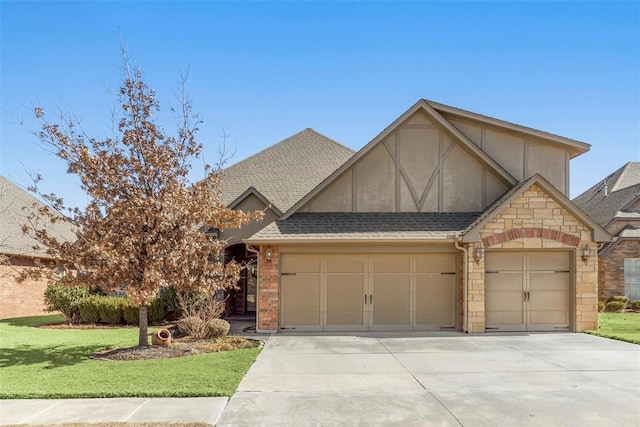 tudor home featuring a garage, a shingled roof, concrete driveway, a front yard, and stucco siding