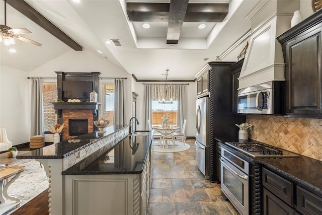 kitchen featuring a sink, visible vents, appliances with stainless steel finishes, decorative backsplash, and an island with sink