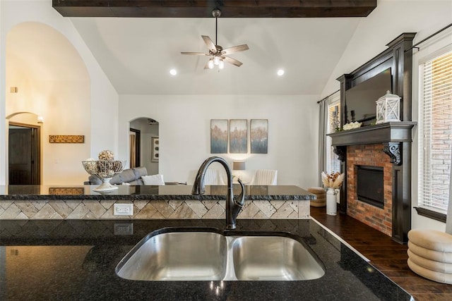 kitchen featuring dark stone countertops, a fireplace, plenty of natural light, and a sink