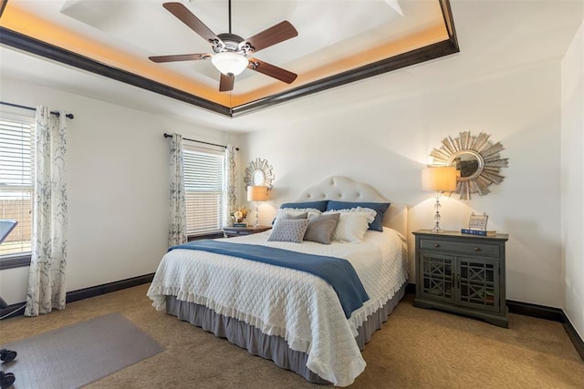 carpeted bedroom featuring ceiling fan, multiple windows, baseboards, and a raised ceiling