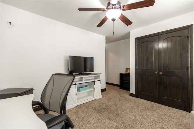 office featuring baseboards, a ceiling fan, and light colored carpet