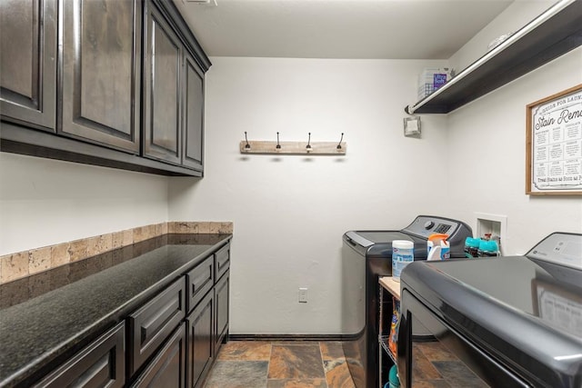 laundry room with cabinet space, washing machine and clothes dryer, stone tile flooring, and baseboards