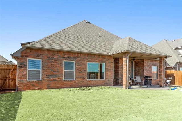 back of house with roof with shingles, brick siding, a ceiling fan, a patio area, and fence