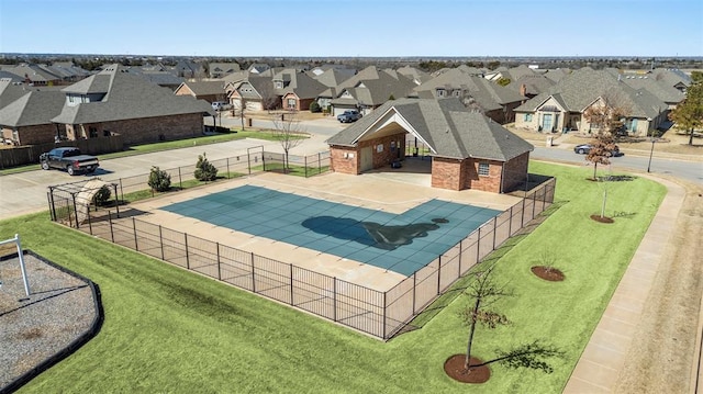 community pool with a patio, fence, and a residential view