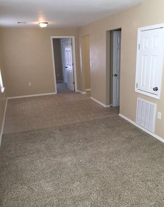 tiled empty room with carpet, visible vents, and baseboards