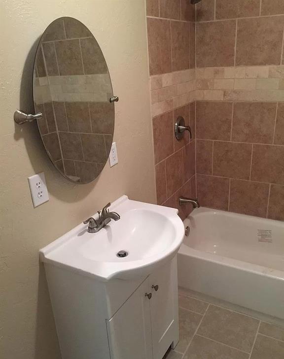 full bathroom with tile patterned floors, shower / tub combination, vanity, and a textured wall