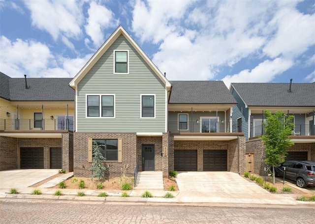 view of front of house featuring driveway, brick siding, an attached garage, and a balcony