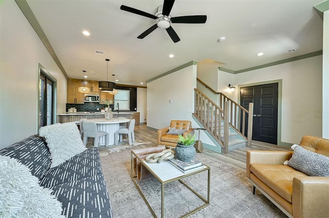 living area with stairway, crown molding, and recessed lighting