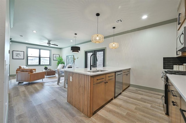 kitchen with light wood finished floors, visible vents, open floor plan, stainless steel appliances, and a sink