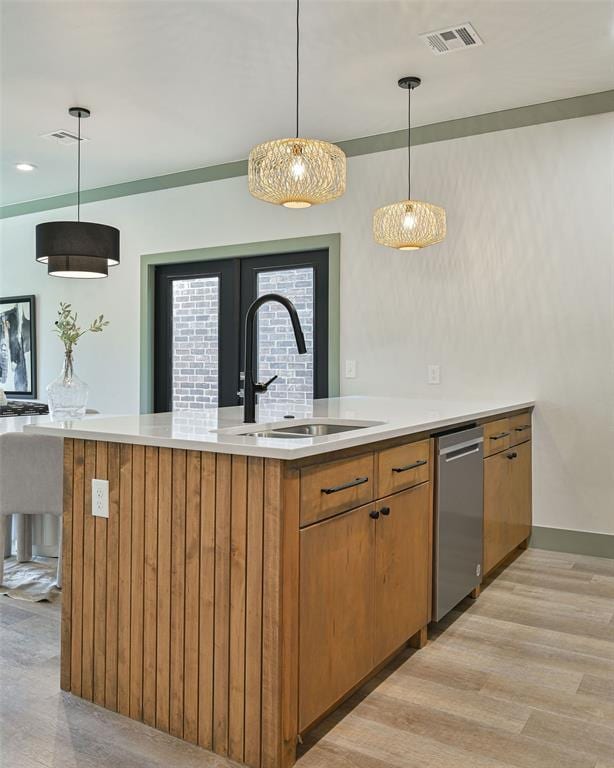 bar with visible vents, dishwasher, hanging light fixtures, light wood-style floors, and a sink