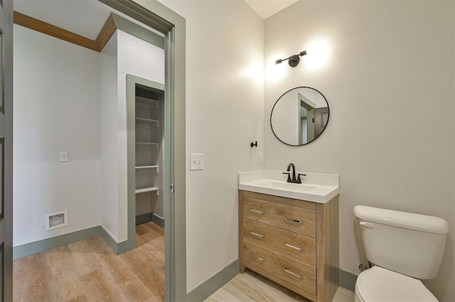 bathroom with toilet, baseboards, wood finished floors, and vanity