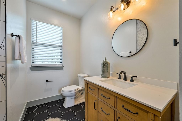 bathroom featuring toilet, tile patterned floors, vanity, and baseboards