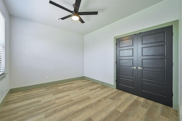 empty room featuring visible vents, a ceiling fan, light wood-style flooring, and baseboards