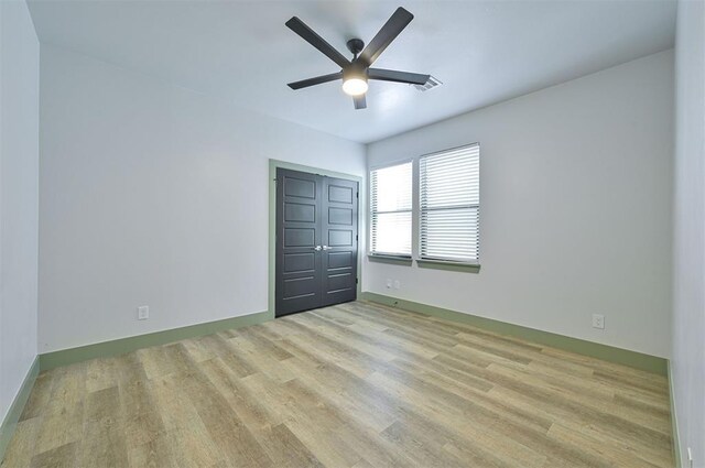 unfurnished bedroom featuring baseboards, a closet, a ceiling fan, and light wood-style floors